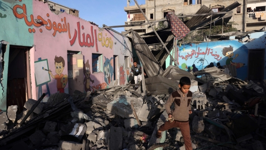 TOPSHOT - Children walk amid the rubble of a school hit during an Israeli strike before the start of a four-day truce in the battles between Israel and Hamas militants, in Rafah in the southern Gaza Strip on November 24, 2023. A four-day truce in the Israel-Hamas war began on November 24, with hostages set to be released in exchange for prisoners in the first major reprieve in seven weeks of war that have claimed thousands of lives. (Photo by Mohammed ABED / AFP)