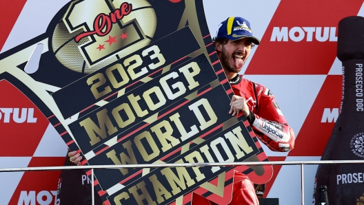 TOPSHOT - Ducati Italian rider Francesco Bagnaia celebrates on the podium after winning the MotoGP Valencia Grand Prix at the Ricardo Tormo racetrack in Cheste, on November 26, 2023. Italy's Francesco Bagnaia enjoyed a dream day as he retained his MotoGP world title and crowned it with victory in the final race of the season in Valencia today. The 26-year-old Ducati rider had been assured of the championship when his sole rival Jorge Martin crashed early in the race. (Photo by JOSE JORDAN / AFP)