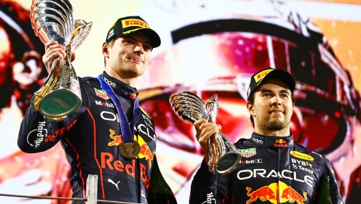 ABU DHABI, UNITED ARAB EMIRATES - NOVEMBER 20: Race Winner Max Verstappen of the Netherlands and Oracle Red Bull Racing and Third placed Sergio Perez of Mexico and Oracle Red Bull Racing celebrate on the podium during the F1 Grand Prix of Abu Dhabi at Yas Marina Circuit on November 20, 2022 in Abu Dhabi, United Arab Emirates. (Photo by Mark Thompson/Getty Images)