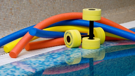 Aqua aerobics equipment. Noodles dumbbells for aqua aerobics lie on the coast in pool