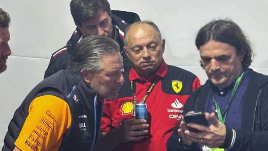 A reporter shows McLaren CEO Zak Brown, lower left, Mercedes team principal Toto Wolff, top left, and Ferrari team principal Frédéric Vasseur a video following the shortened first practice session for the Formula One Las Vegas Grand Prix auto race, Thursday, Nov. 16, 2023, in Las Vegas. (AP Photo/Jenna Fryer)