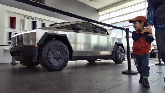 A young visitor takes a look at a Tesla Cybertruck on display at Tesla in Buena Park, Calif., Sunday Dec. 3, 2023. With manufacturing kinks still to be worked out, Tesla has delivered the first dozen or so of its futuristic Cybertruck pickups to customers. (AP Photo/Richard Vogel)