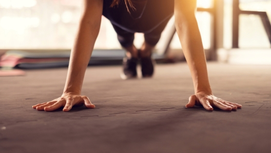 Close up woman hand doing push ups exercise in a gym in morning, sunlight effect.