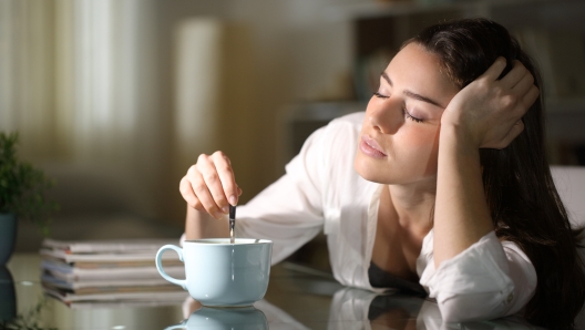 Sleepy woman stirring coffee in the morning