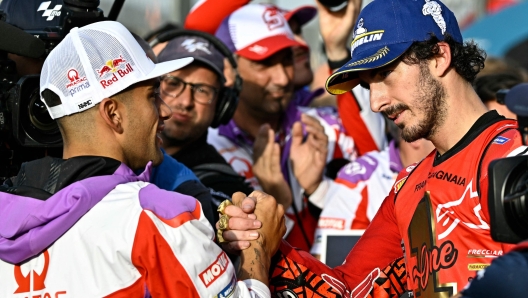 Ducati Italian rider Francesco Bagnaia (R) shakes hands with Ducati Spanish rider Jorge Martin after winning the MotoGP Valencia Grand Prix at the Ricardo Tormo racetrack in Cheste, on November 26, 2023. Italy's Francesco Bagnaia enjoyed a dream day as he retained his MotoGP world title and crowned it with victory in the final race of the season in Valencia today. The 26-year-old Ducati rider had been assured of the championship when his sole rival Jorge Martin crashed early in the race. (Photo by JAVIER SORIANO / AFP)