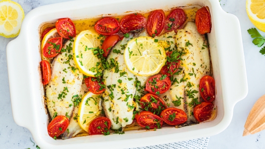 Baked cod fillet with cherry tomatoes and butter, top view. Healthy diet recipe.