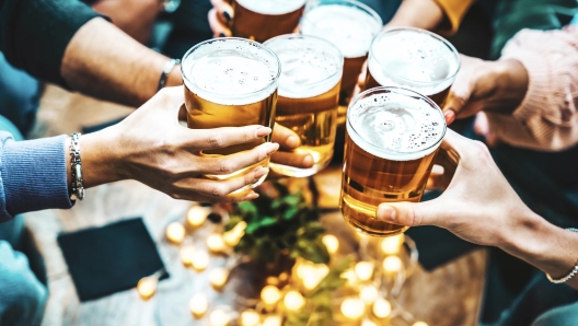 Group of people drinking beer at brewery pub restaurant - Happy friends enjoying happy hour sitting at bar table - Closeup image of brew glasses - Food and beverage lifestyle concept