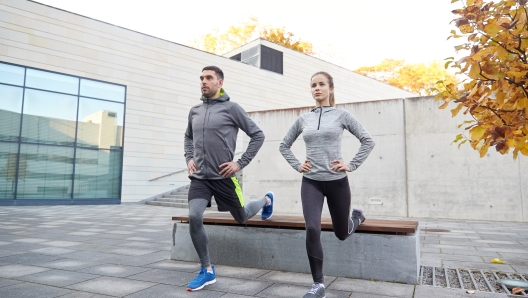 fitness, sport, people, exercising and lifestyle concept - couple doing lunge exercise on city street