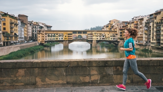 Fitness woman jogging in front of ponte vecchio in florence, italy