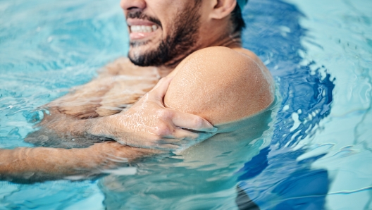 Man in swimming pool, athlete with injury and shoulder pain, fitness with sport accident and muscle ache during workout. Water sports, stroke mistake and swimmer, exercise and problem with arm