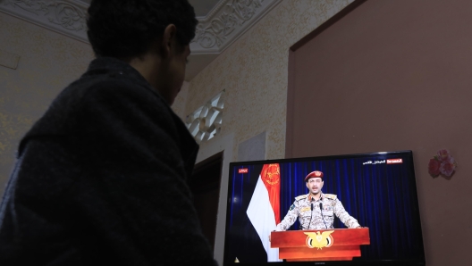 epa11070839 A person watches a TV statement by the Houthis' military spokesman Yahya Sarea following US-UK-carried out airstrikes on Yemen, in Sana'a, Yemen, 12 January 2024. According to the Houthis military spokesman Yahya Sarea, five Houthi fighters were killed and six others wounded in a total of 73 airstrikes carried out by the United States and the United Kingdom against several Houthis-controlled sites in Yemen in response to Houthis attacks in the Red Sea. The US Department of Defense had announced in December 2023 a multinational operation to safeguard trade and to protect ships in the Red Sea amid the recent escalation in Houthi attacks. Houthis vowed to attack Israeli-bound ships and prevent them from navigating in the Red Sea and the Bab al-Mandab Strait in retaliation for Israel's airstrikes on the Gaza Strip, according to Sarea.  EPA/YAHYA ARHAB