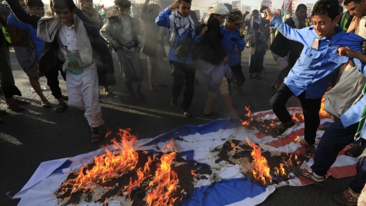 epa11071716 People burn Israeli and US flags during a protest against a multinational operation to safeguard Red Sea shipping following US and UK airstrikes on Houthis military sites, in Sana'a, Yemen, 12 January 2024. According to the Houthis military spokesman Yahya Sarea, five Houthi fighters were killed and six others wounded in a total of 73 airstrikes carried out by the United States and the United Kingdom against several Houthis-controlled sites in Yemen in response to Houthis attacks in the Red Sea. The US Department of Defense had announced in December 2023 a multinational operation to safeguard trade and to protect ships in the Red Sea amid the recent escalation in Houthi attacks. Houthis vowed to attack Israeli-bound ships and prevent them from navigating in the Red Sea and the Bab al-Mandab Strait in retaliation for Israel's airstrikes on the Gaza Strip, according to Sarea.  EPA/YAHYA ARHAB