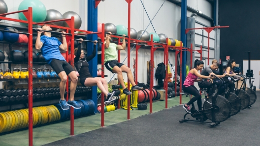 Group of athletes doing pull ups and air bike in the gym