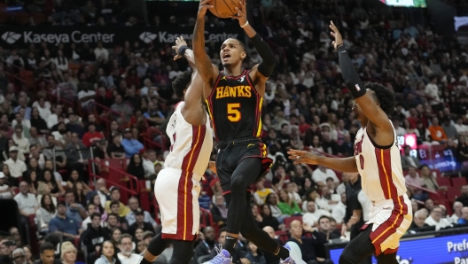 Atlanta Hawks guard Dejounte Murray (5) drives to the basket as Miami Heat guard Kyle Lowry, left, and guard Josh Richardson (0) defend during the first half of an NBA basketball game Friday, Dec. 22, 2023, in Miami. (AP Photo/Lynne Sladky)