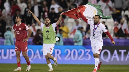 Tajikistan's Soirov Rustam, center, and Tajikistan's Vaysiddin Safarov, right, hold up their national flag after beating Lebanon during the Asian Cup Group A soccer match between Lebanon v Tajikistan at Jassim Bin Hamad Stadium in Doha, Qatar, Monday, Jan. 22, 2024. At left is Lebanon's Hasan Spour. (AP Photo/Aijaz Rahi)