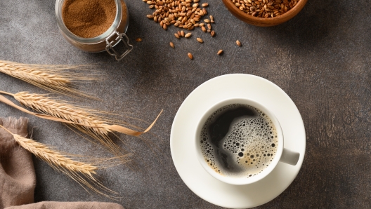 Cooking healthy barley coffee on brown background. Best natural caffeine free organic coffee alternative. Coffee substitute beverage made of a blend of roasted barley. View from above.