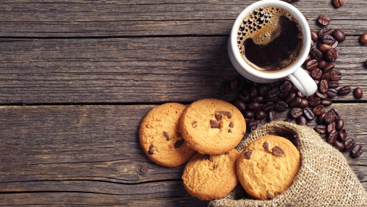 Cup of coffee and chocolate cookies in sack on vintage wooden table