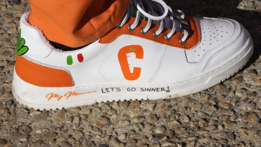 The "Carota Boys" logo is seen on a shoe worn by a Jannik Sinner supporter as the group cheers outside the Pala Alpitour before the singles tennis match between Italy's Jannik Sinner and Greece's Stefanos Tsitsipas, of the ATP World Tour Finals at the Pala Alpitour, in Turin, Italy, Sunday, Nov. 12, 2023. They?ve quickly become some of the most recognizable fans in tennis. And what began as a spur-of-the-moment idea between six fans of Jannik Sinner dressed as carrots has turned into a fully sponsored globe-trotting enterprise. After first appearing at the Italian Open in May, the orange-clad ?Carota Boys? quickly picked up support from coffee maker Lavazza and were sent to support Sinner at the French Open, Wimbledon and the U.S. Open. (AP Photo/Antonio Calanni) (AP Photo/Antonio Calanni)