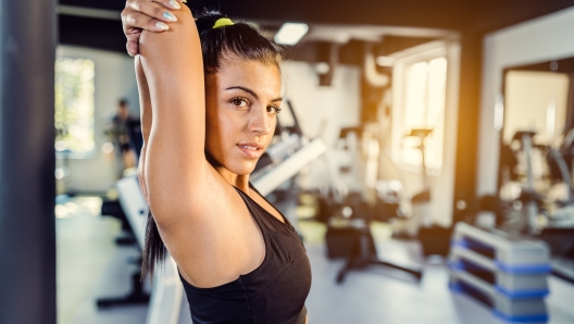 Young woman stretches her shoulders before training.