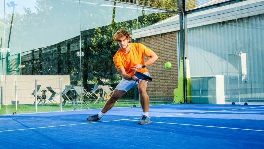 Padel match in a blue grass padel court - Handsome boy player playing a match