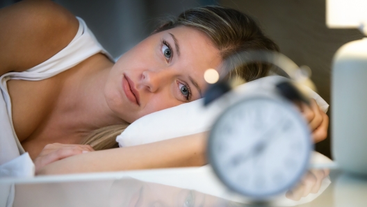 Shot of beautiful young exhausted woman suffering insomnia lying on bed in bedroom at home.