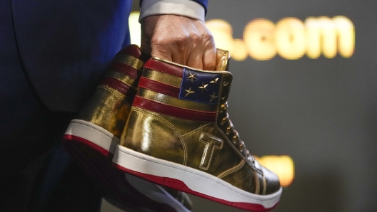 Republican presidential candidate former President Donald Trump holds gold Trump sneakers at Sneaker Con Philadelphia, an event popular among sneaker collectors, in Philadelphia, Saturday, Feb. 17, 2024. (AP Photo/Manuel Balce Ceneta)