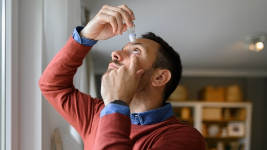 Close-up of young man applying eye drops to treat dry eye and irritation at home