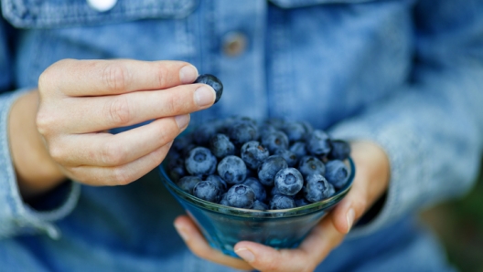 Woman eating ripe blueberries, healthy berries.