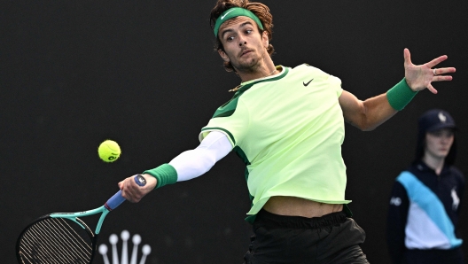 Italy's Lorenzo Musetti hits a return against France's Luca Van Assche during their men's singles match on day four of the Australian Open tennis tournament in Melbourne on January 17, 2024. (Photo by Anthony WALLACE / AFP) / -- IMAGE RESTRICTED TO EDITORIAL USE - STRICTLY NO COMMERCIAL USE --