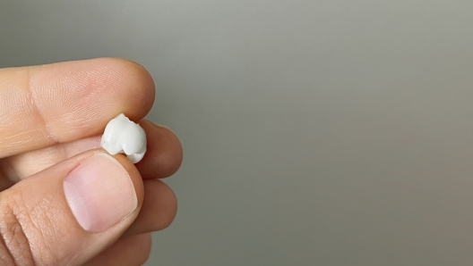 White fallen baby tooth in hand on gray background, macro