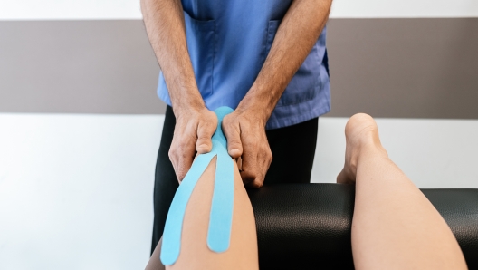 Physiotherapist giving calf therapy to a woman in clinic. Physical treatment concept