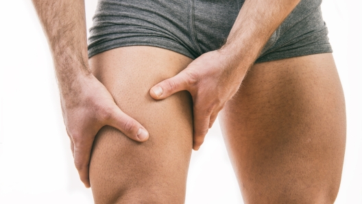 Man with quadriceps pain over white background