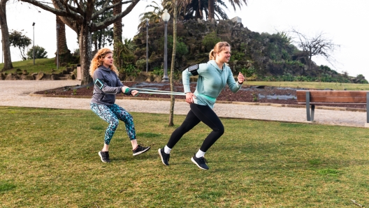 Women doing work out at park, strengthening running exercise - two beautiful young women in Porto training together on a cloudy day - outdoor activities and sport