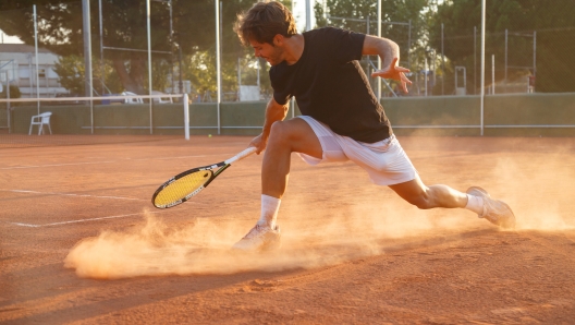 Professional tennis player man playing on court in afternoon.