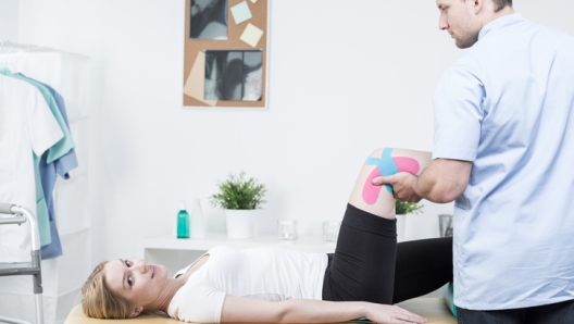 Young physiotherapist using physio tape for knee