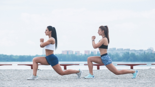 two fit woman doing stretches after running workout. Active lifestyle on seafront