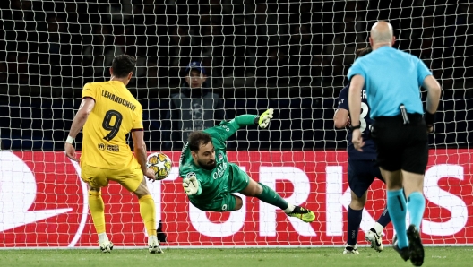 Paris Saint-Germain's Italian goalkeeper #99 Gianluigi Donnarumma (C) dives for the ball during the UEFA Champions League quarter final first leg football match between Paris Saint-Germain (PSG) and FC Barcelona at the Parc des Princes stadium in Paris on April 10, 2024. (Photo by FRANCK FIFE / AFP)