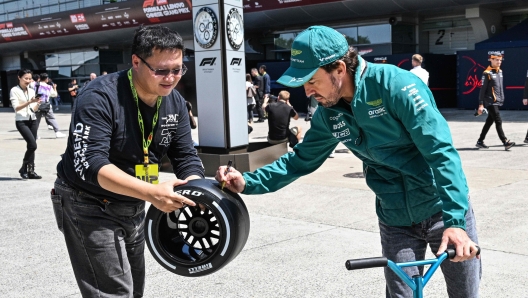 TOPSHOT - Aston Martin's Spanish driver Fernando Alonso signs an autograph for a fan in the paddock at the Shanghai International circuit ahead of the Formula One Chinese Grand Prix in Shanghai on April 18, 2024. (Photo by Hector RETAMAL / AFP)