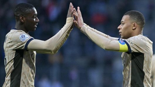 Paris Saint-Germain's French forward #07 Kylian Mbappe (R) and Paris Saint-Germain's French forward #23 Randal Kolo Muani (L) high five each other as they celebrate their victory at the end of the French L1 football match between FC Lorient and Paris Saint-Germain (PSG) at the Stade du Moustoir in Lorient, western France, on April 24, 2024. (Photo by DAMIEN MEYER / AFP)