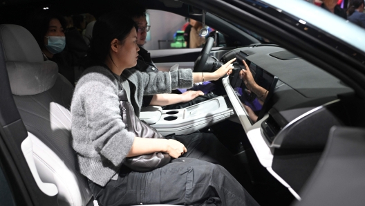 Visitors inspect a Xpeng G9 vehicle at the Beijing Auto Show on April 29, 2024. (Photo by Pedro PARDO / AFP)