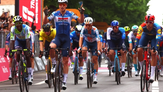 Winner Team Soudal-Quick Step's Belgian rider Tim Merlier (C), flanked by second placed Team Lidl-Trek's Italian rider Jonathan Milan (R) and third placed Team Intermarche's Eritrean rider Biniam Girmay (L), cross the finish line of the 3rd stage of the 107th Giro d'Italia cycling race, 166 km between Novara and Fossano, on May 6, 2024 in Fossano. (Photo by Luca Bettini / AFP)