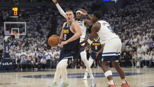 Denver Nuggets center Nikola Jokic, left, works toward the basket as Minnesota Timberwolves forward Jaden McDaniel, center, and guard Anthony Edwards defend during the second half of Game 4 of an NBA basketball second-round playoff series, Sunday, May 12, 2024, in Minneapolis. (AP Photo/Abbie Parr)