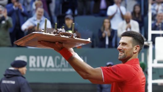 epa11361402 Serbia's Novak Djokovic shows to spectators his birthday cake after he won the men's singles second round of the ATP 250 Geneva Open tournament in Geneva, Switzerland, 22 May 2024.  EPA/SALVATORE DI NOLFI