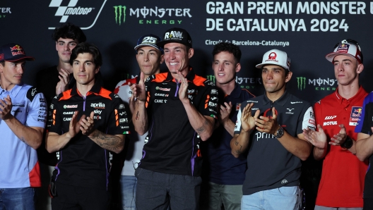 Aprilia Spanish rider Aleix Espargaro (C) applauds flanked by other riders, after announcing his retirement from MotoGP at the end of the 2024 season, during a press conference at the Catalunya racetrack in Montmelo, near Barcelona, on May 23, 2024, ahead of the Catalunya Moto GP Grand Prix. (Photo by LLUIS GENE / AFP)