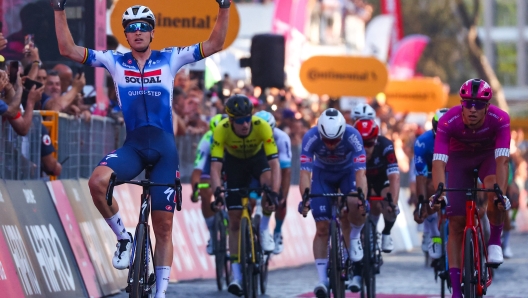 Team Soudal-Quick Step's Belgian rider Tim Merlier (L) celebrates his stage victory ahead of second-placed Team Lidl-Trek's Italian rider Jonathan Milan (R) wearing the best sprinter's purple jersey as they cycle past the finish line to win the 21st and last stage of the 107th Giro d'Italia cycling race, 125km from Rome to Rome on May 26, 2024. (Photo by Luca Bettini / AFP)