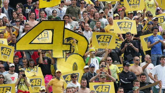 20070603 - SCARPERIA - FIRENZE - SPO - MOTO: ITALIA; ROSSI TORNA A VINCERE, E' TROPPO BELLO. Fans del pilota italiano Valentino Rossi esultano al termine della gara del Gran Premio d'Italia classe MotoGp, oggi sul circuito del Mugello. Valentino Rossi e' tornato. La pista del Mugello incorona il campione pesarese, che per il sesto anno consecutivo fa suo il Gp d'Italia: va a vincere nonostante un avvio tutt'altro che brillante. Partito dalla terza posizione in griglia e scivolato ottavo dopo il primo giro, Rossi e' stato protagonista di una rimonta che lo ha portato a guadagnare la testa della corsa al nono giro, e che ha conservato fino al traguardo. La Yamaha stavolta ha sfrecciato davanti alla Honda dello spagnolo Daniel Pedrosa e alle Ducati del brasiliano Alex Barros, vincitore nel 2001 nella classe 500, e di Casey Stoner, quarto. 
ANSA/MAURIZIO DEGL'INNOCENTI/DRN