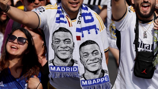 (FILES) Supporters wearing football scarves depicting French footballer Kylian Mbappe cheer prior Real Madrid's celebration for winning 2024 Spanish La Liga title at Cibeles square in Madrid on May 12, 2024. Kylian Mbappe has signed for Real Madrid, according to the club, AFP reports on June 3, 2024. (Photo by OSCAR DEL POZO / AFP)