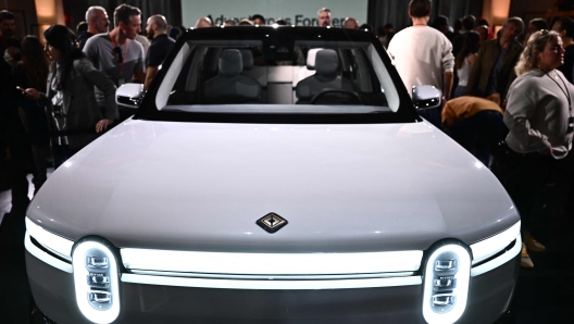 TOPSHOT - Attendees look at the new Rivian R2 electric vehicle at the Rivian South Coast Theater in Laguna Beach, California, on March 7, 2024. (Photo by Patrick T. Fallon / AFP)