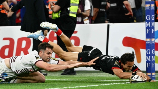 Toulouse's Italian full back Ange Capuozzo (R) dives and scores a try as Bordeaux-Begles' French wing Damian Penaud (L) tackles  during the French Top 14 rugby union final match between the Stade Toulousain (Toulouse) and Union Bordeaux-Begles (UBB) at the Velodrome Stadium in Marseille, southeastern france, on June 28, 2024. (Photo by Christophe SIMON / AFP)