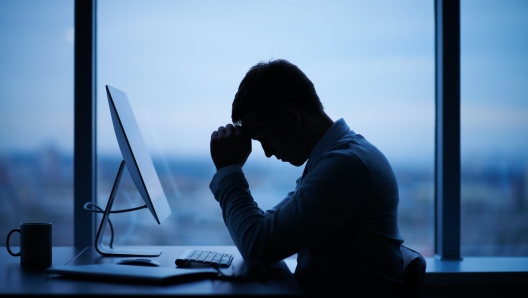 Tired or stressed businessman sitting in front of computer in office